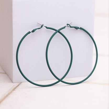 Green hoop earrings on a white box with a light background