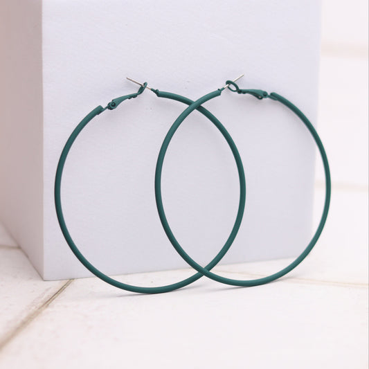 Green hoop earrings on a white box with a light background
